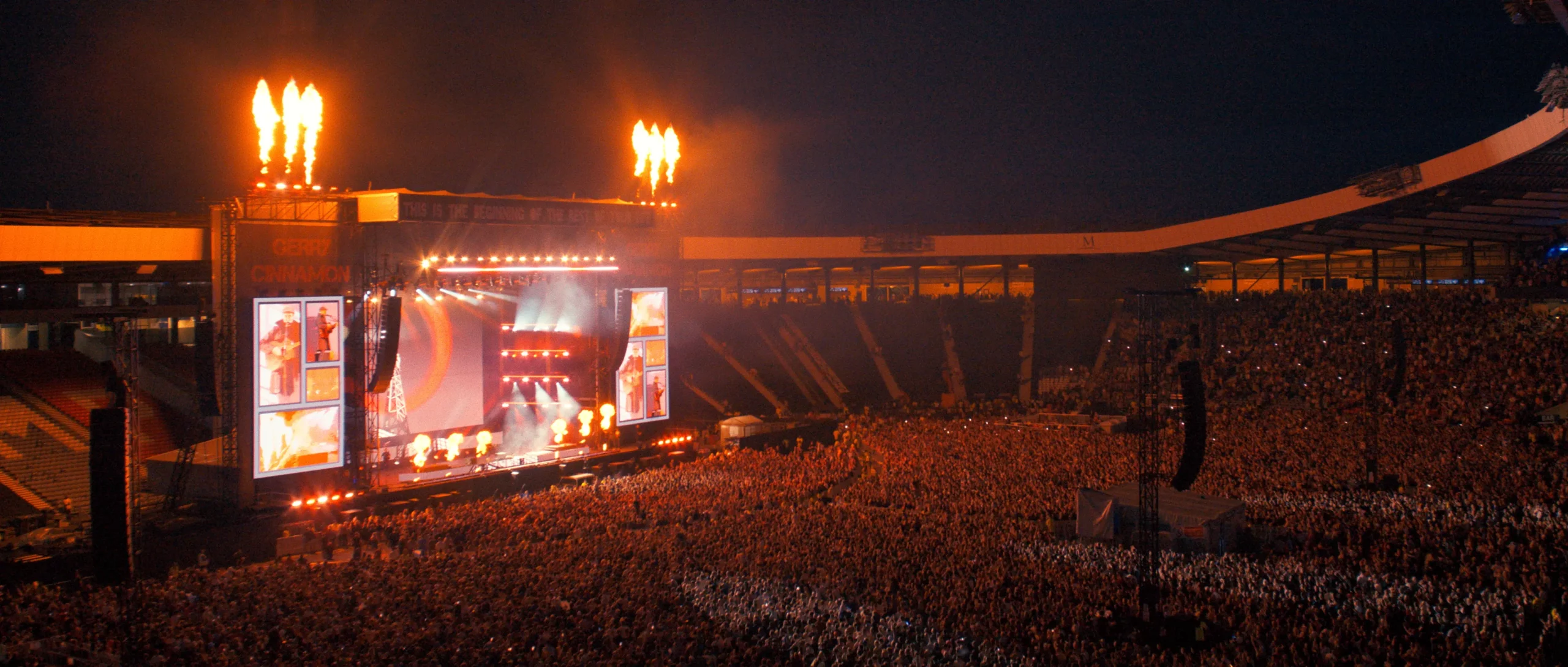 Wide stadium shot of fire igniting and a huge crowd watching Gerry Cinnamon at Hampden Park.